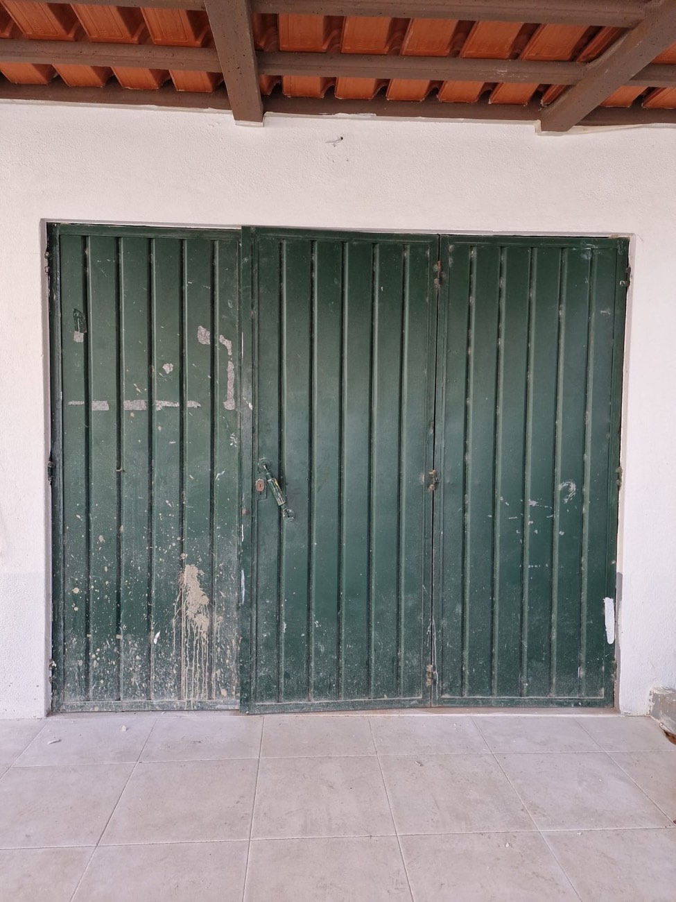 Portão de garagem verde com a tinta a descascar