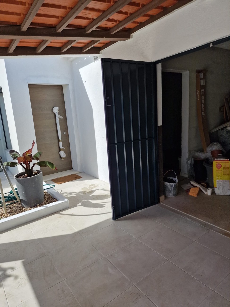 Portão de garagem pintado em grafite, ao lado da porta de entrada